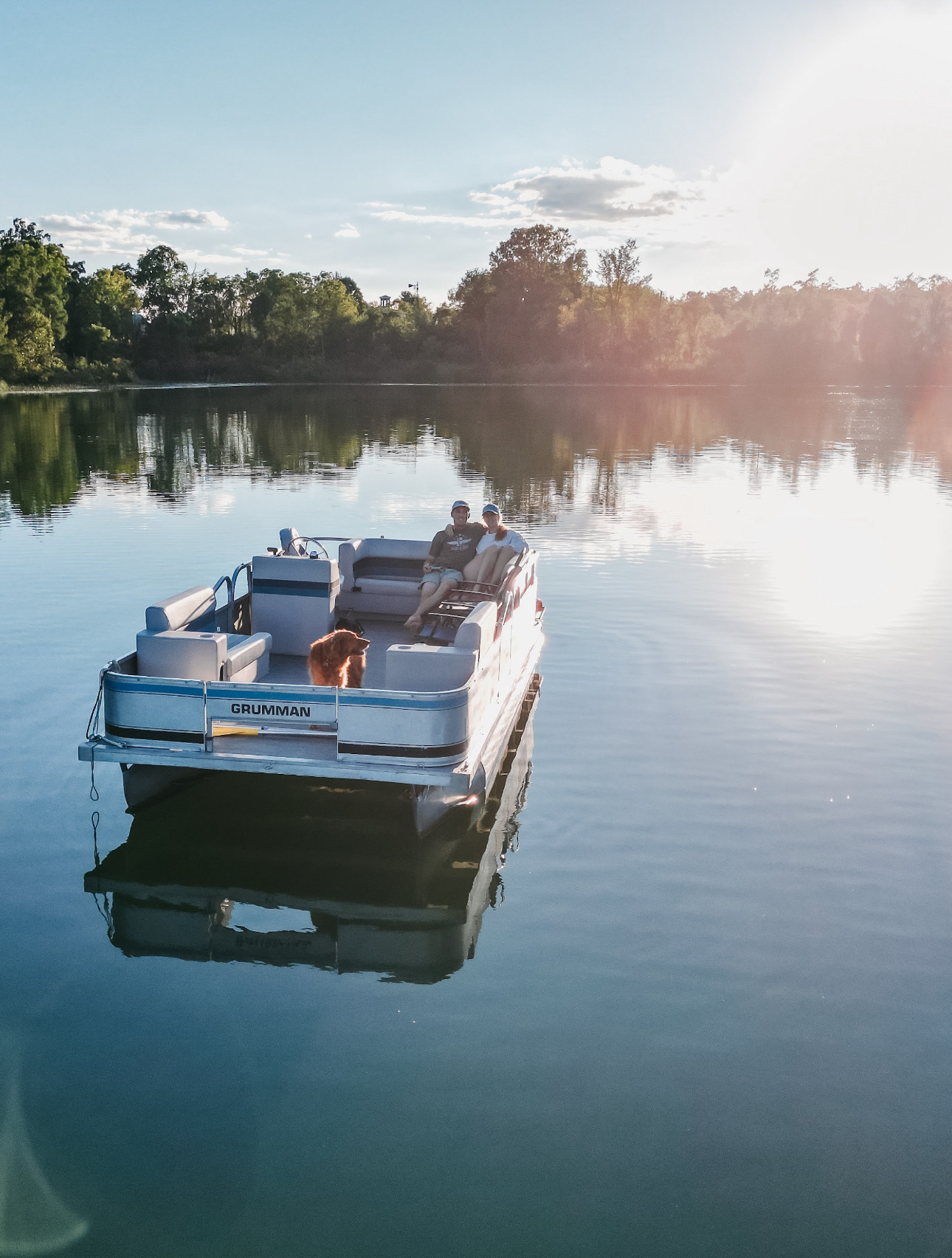 Couple and their golden retriever relaxing on the Grumman pontoon out on Lake Huyck